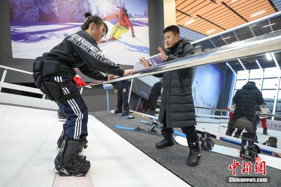 1月6日，一位体育老师指导学生在室内滑雪模拟机上学习“滑雪”。 瞿宏伦 摄