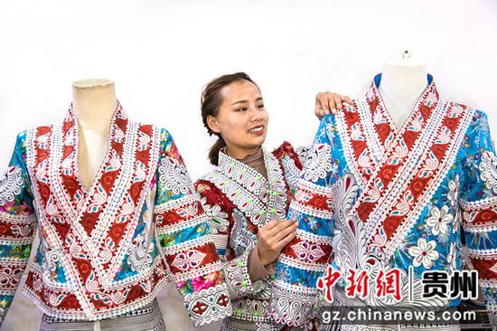 2022年1月11日，贵州省黔西市林泉镇高锦社区一家苗族服饰加工车间，苗族姑娘整理刚加工好的成品新服饰。