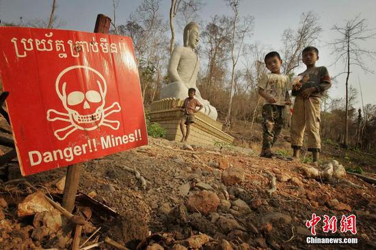 当地时间2022年1月11日，据英国《卫报》报道，去年6月光荣退役的8岁柬埔寨“功勋扫雷鼠”马加瓦于上周末去世。过去5年，这只巨鼠帮助柬埔寨成功扫除总计22.5万平方米土地上的71枚地雷及38枚未爆炸弹。它于2020年获得荣誉勋章。负责培训马加瓦的比利时慈善机构APOPO表示，马加瓦身体一直很健康，它上周大部分时间都在玩耍，但到了周末，它的脚步慢下来了，睡觉的时间多起来，对食物也兴致恹恹。资料图为柬埔寨的孩子们在有地雷提示标牌边玩耍。图片来源：视觉中国