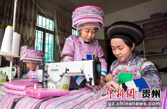 2022年1月10日，贵州省黔西市红林彝族苗族乡鱼塘村一家苗族服饰加工车间，村民在制衣过程中进行交流。