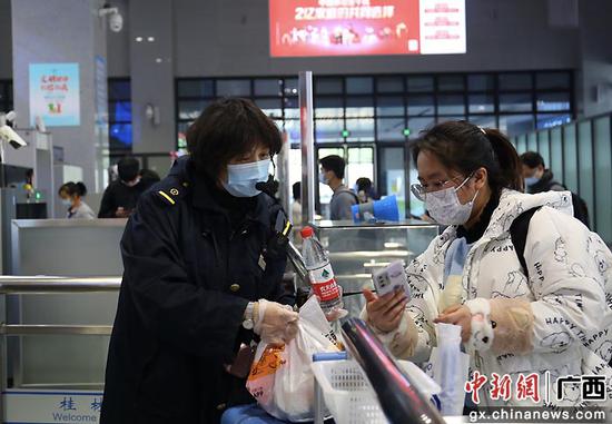 图为桂林火车站工作人员对学生旅客行程码进行核验。郑长贤 摄