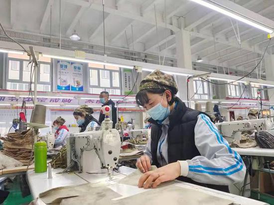 村民在东梁产业示范园康乐制衣厂加班工作。