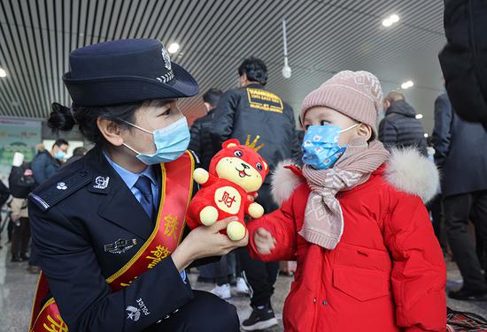 民警向候车小朋友赠送小虎玩偶。
