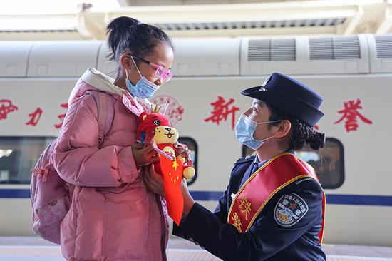 民警向候车小朋友赠送小虎玩偶。