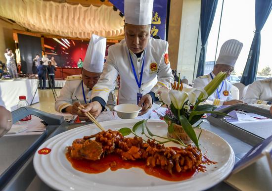 专业评委品尝参赛选手用当地野生鱼烹饪的美食并打分。中新社记者 刘新 摄