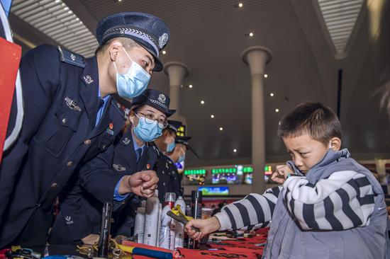 民警在安全宣传现场向小旅客讲解弹弓的危害性并叮咛春节期间安全注意事项。