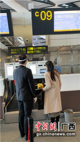 南宁机场工作人员协助旅客办理自助行李托运。罗先彬 摄