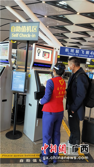 南宁机场志愿者协助旅客办理自助值机。罗先彬 摄