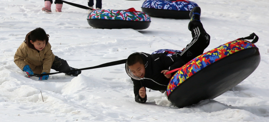 小朋友拉滑雪圈玩耍取乐。华岩明摄