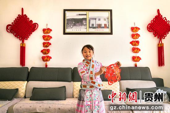 2022年1月23日，贵州省黔西市新仁苗族乡化屋村易地扶贫搬迁安置点，苗族村民赵玉学家小女儿展示她的剪纸作品。