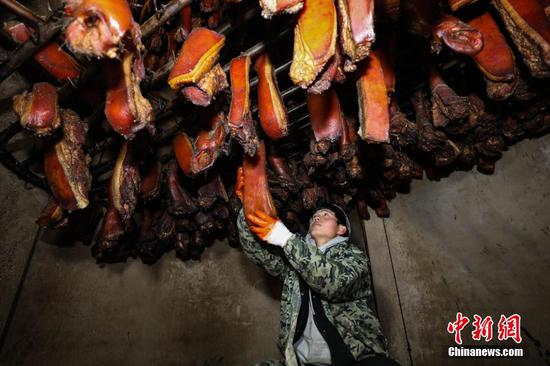1月26日，一位工作人员在悬挂熏烤的腊肉半成品。 瞿宏伦 摄