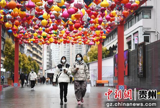 在贵阳市南明区青云路步行街，市民走在挂满灯笼的街道上。