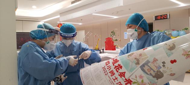 天津理工大学相关负责人将学生设计的战“疫”艺术作品制成的年历和装有糖瓜的福袋送到一中心医院。  天津市第一中心医院供图