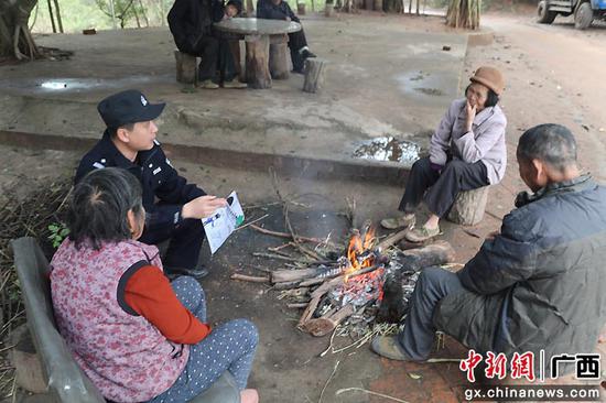 民警刘欣拿着绘画在和壮族村民宣传铁路安全知识。陈大鹏  供图