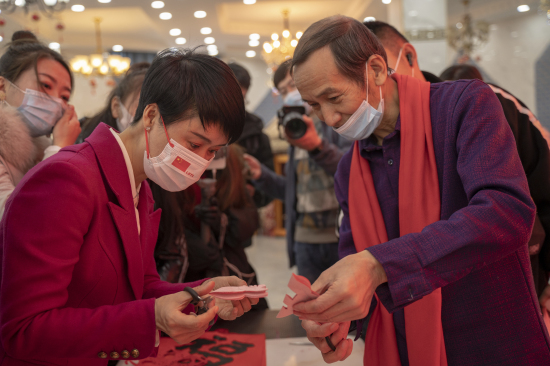 伊犁州文化和旅游局党组成员、副局长贺娇龙向伊宁市剪纸非遗传承人夏雄飞学习剪纸技艺。