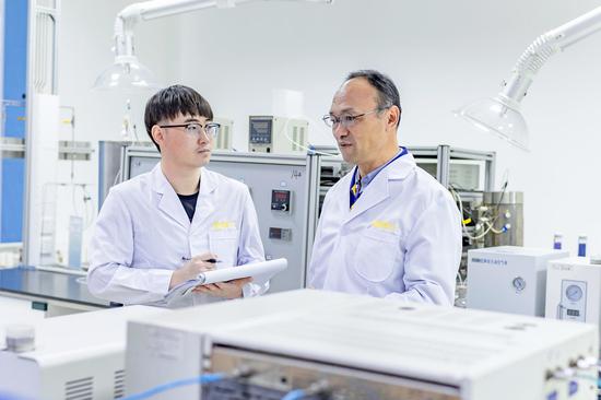 熊新阳（右）与同事在实验室里一起讨论技术问题。