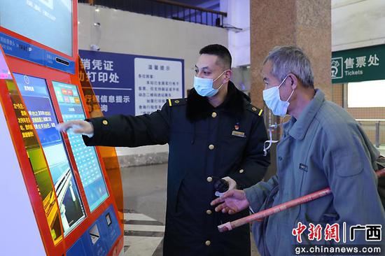 图为桂林火车站客运值班员王海涛在候车厅帮助老年旅客查询候车区域。郑长贤 摄