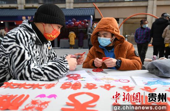 2月3日，人们在贵阳市南明区青云路步行街体验民间剪纸艺术。