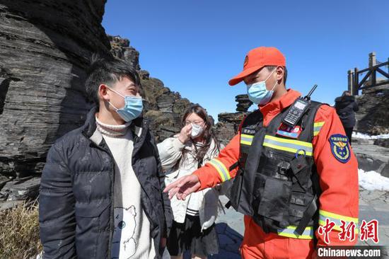 2月14日，一名消防救援人员在梵净山顶给游客宣讲安全须知。　瞿宏伦 摄