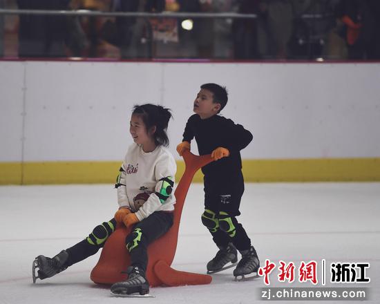 一个小朋友在推着另一个小朋友体验滑冰。 赵阳（实习生） 摄