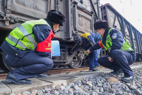 民警与车辆列检人员了解货运列车编组情况。
