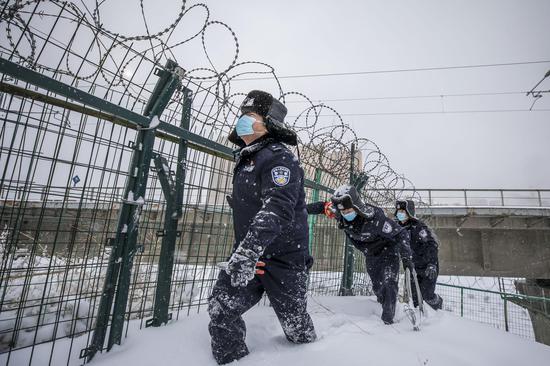 民警在雪中对高铁护栏进行安全巡查。