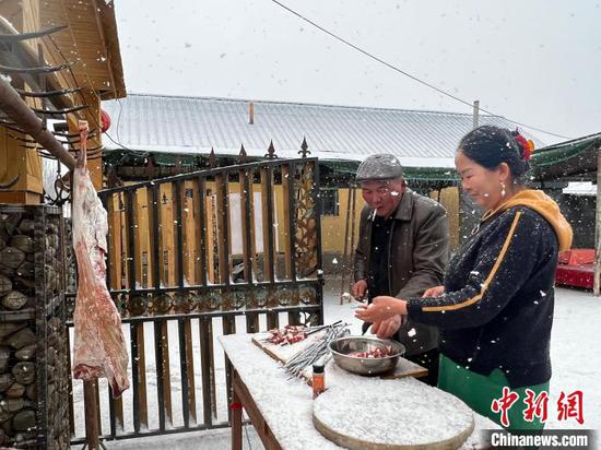 艾斯和妻子正准备丰盛的午餐，家里要来游客，两人在雪花飞舞中串起烤肉。　冀江彤 摄