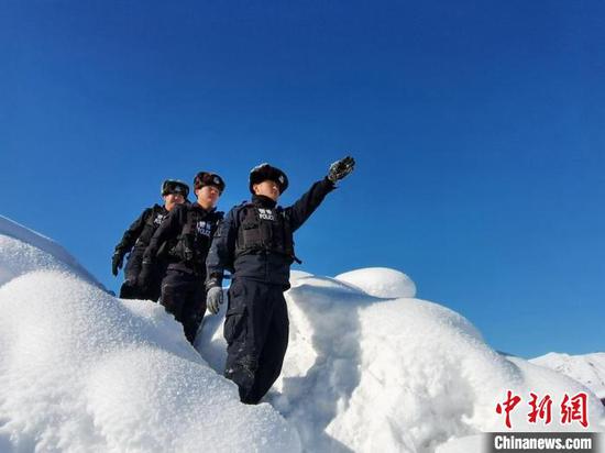 3月2日，新疆阿勒泰地区布尔津县禾木边防派出所的民警登上山顶。　刘是何　摄
