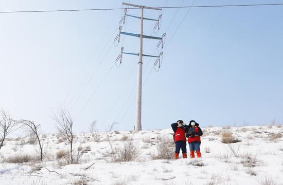 3月1日，新疆乌鲁木齐供电公司员工周磊和徒弟陈伟在兰新高铁沿线220千伏满宫牵一线经过的荒山上开展输电线路和铁塔巡检工作，以确保高铁列车“电力满满”、群众平安出行。广明伟 摄