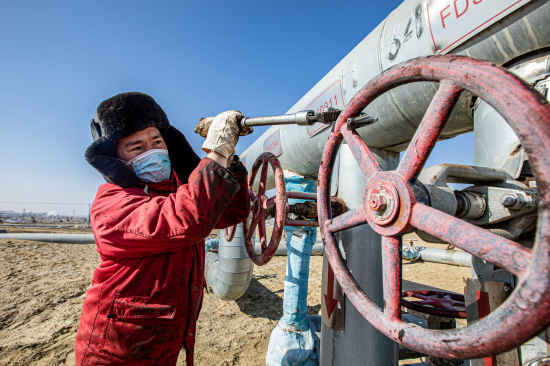 新疆油田员工开启管汇单井注气闸门。
