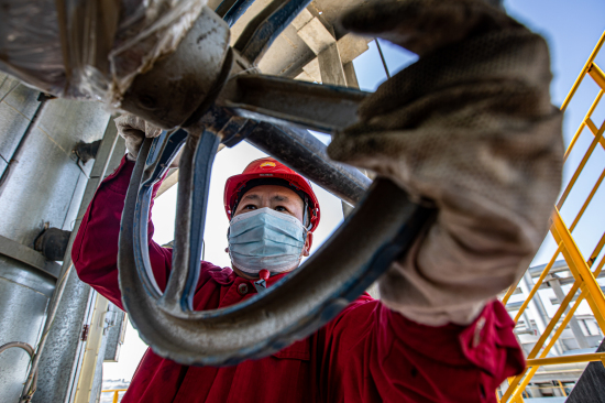 新疆油田员工对密闭站空冷器进行日常检查。