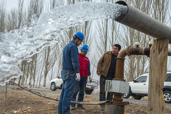 國網阿克蘇供電公司員工在溫宿縣古勒阿瓦提鄉了解棉農春灌用電設備運行情況。（王衛強 攝）