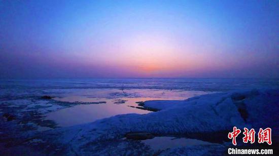 夕阳西下时分，岸边融化的湖水与裂冰和霞光绚烂的天空交融在一起，强烈的色彩碰撞构成一幅浓烈的油画。　王荣曌熙　摄