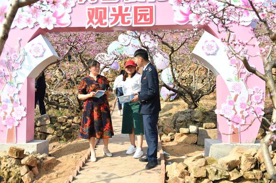 税务人员在威宁县龙场镇首届桃花节上向游客宣传社保费政策。张泉辉摄
