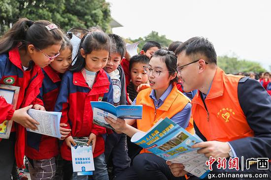 图为桂林地区青年志愿者为同学细致讲解宣传册上的内容。文毅 摄