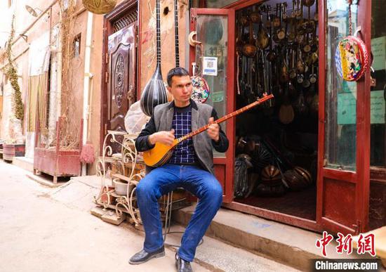 图为马木提江·亚森向记者展示民族乐器弹奏技巧。　李彩琴 摄