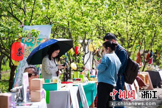 游客参观花界柿集，在龙井茶摊位前驻足品茗。 芳菲  供图