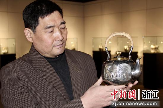 
程志芳展示自己以中国农历虎年为主题创作的《虎兆丰年》银壶。  张斌 摄
