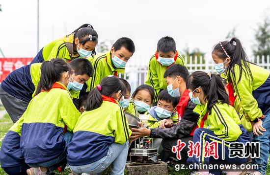 3月22日，学生在贵州省黔西市气象局听业务员介绍翻斗式雨量筒工作原理。