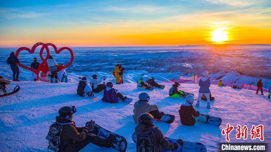 新疆阿勒泰地区今年前三月接待游客同比增长近三成。图为近日游客在阿勒泰的滑雪场玩“滑雪追夕阳”。　阿勒泰文旅局供图。