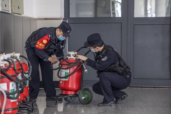 民警对站内旅客进站通道内消防器材进行安全检查。
