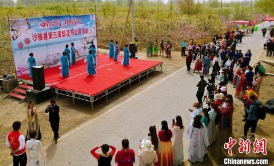 新疆沙雅县第三届梨花节云游活动上村民们在表演扇子舞。　程磊　摄