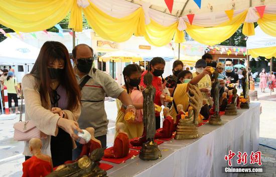 4月14日，泰国曼谷，市民在一处佛寺内为佛像浇水“浴佛”。时值泰历新年泼水节（宋干节）假期，曼谷街头不见“水花四溅”的景象。由于疫情原因，泰国政府规定今年泼水节不得进行泼水、相互抹粉等活动，但可以举行传统文化活动。中新社记者 王国安 摄