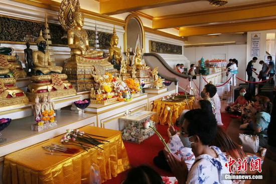4月14日，泰国曼谷，市民在一处佛寺内礼佛。时值泰历新年泼水节（宋干节）假期，曼谷街头不见“水花四溅”的景象。由于疫情原因，泰国政府规定今年泼水节不得进行泼水、相互抹粉等活动，但可以举行传统文化活动。中新社记者 王国安 摄
