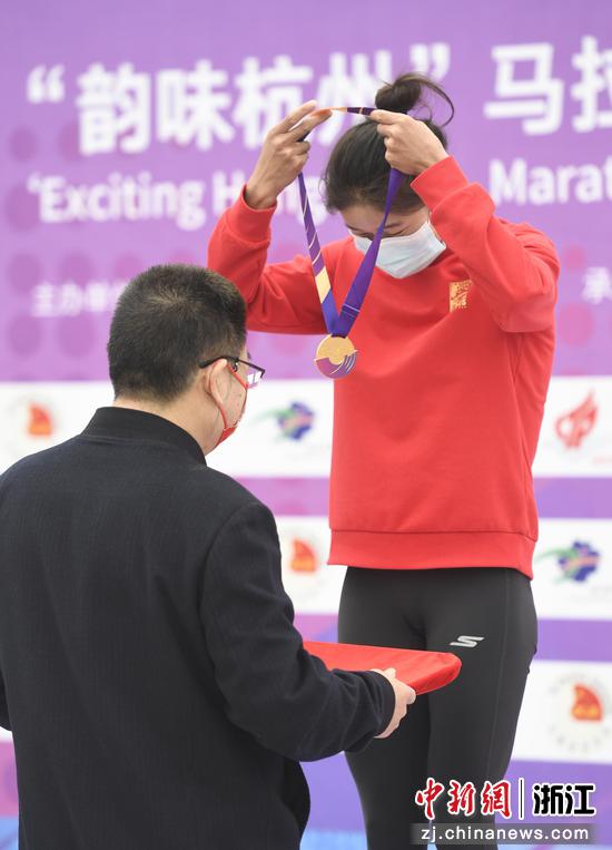  女子马拉松获奖选手在颁奖仪式上为自己戴上奖牌。 王刚 摄