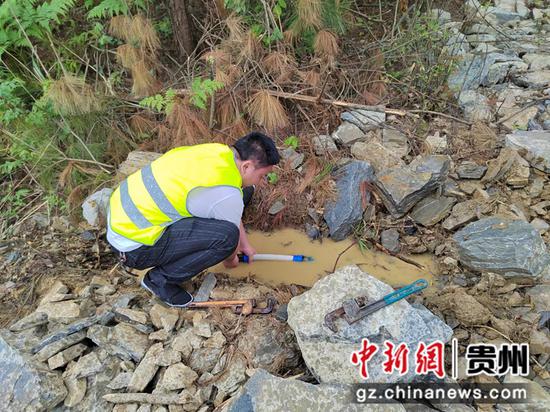 图为贵州龙里县谷脚镇分公司管水员挖开石堆进行管道维护