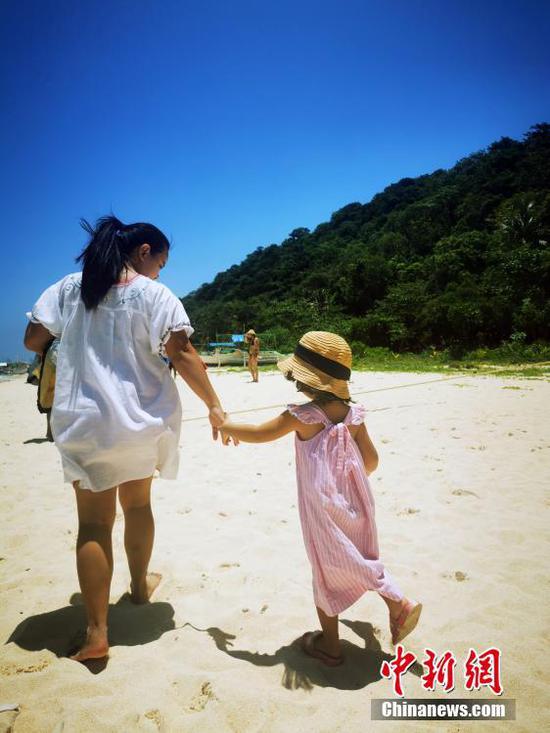当地时间4月19日，在菲律宾长滩岛白沙滩，一对游客母女在沙滩漫步。4月1日起，菲律宾宣布对全球完全接种疫苗的旅客开放，国际航班逐渐恢复。 中新社记者 关向东 摄