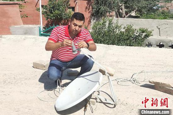 居马洪·乌苏尔在为村民修理电视信号接收器。　孙长金 摄