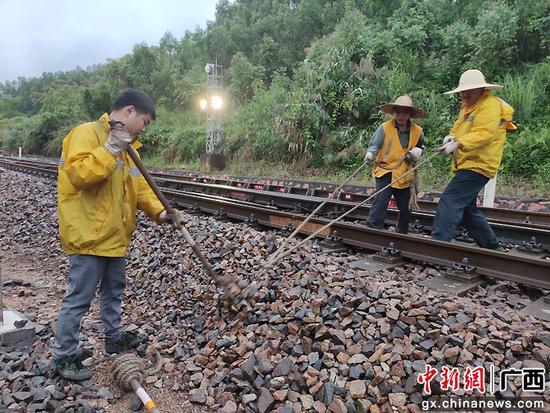 图为玉林工务段职工在益湛线上冒雨进行线路均匀边坡石碴作业。唐诗宇  摄