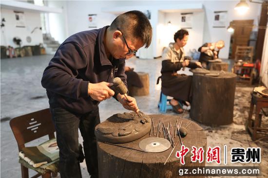 在岑巩县思州砚传承基地，传承人周永平正在雕刻砚台。